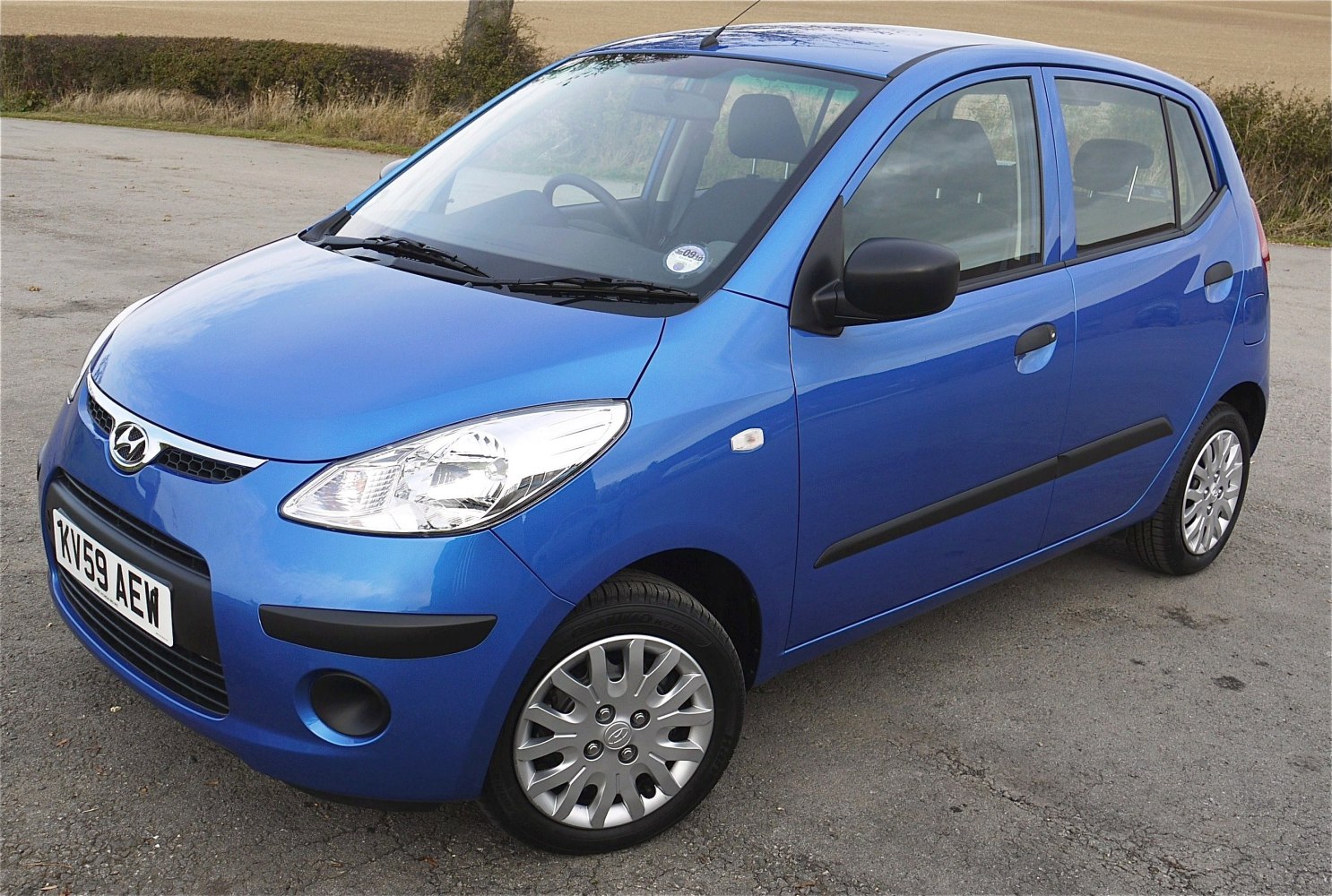 Blue compact hatchback front-side view with headlight and alloy wheels