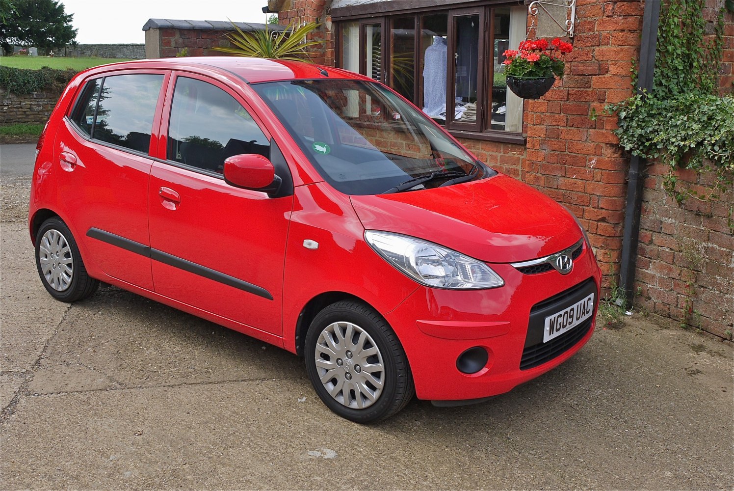 Red compact hatchback with distinctive headlights and black bumper strips