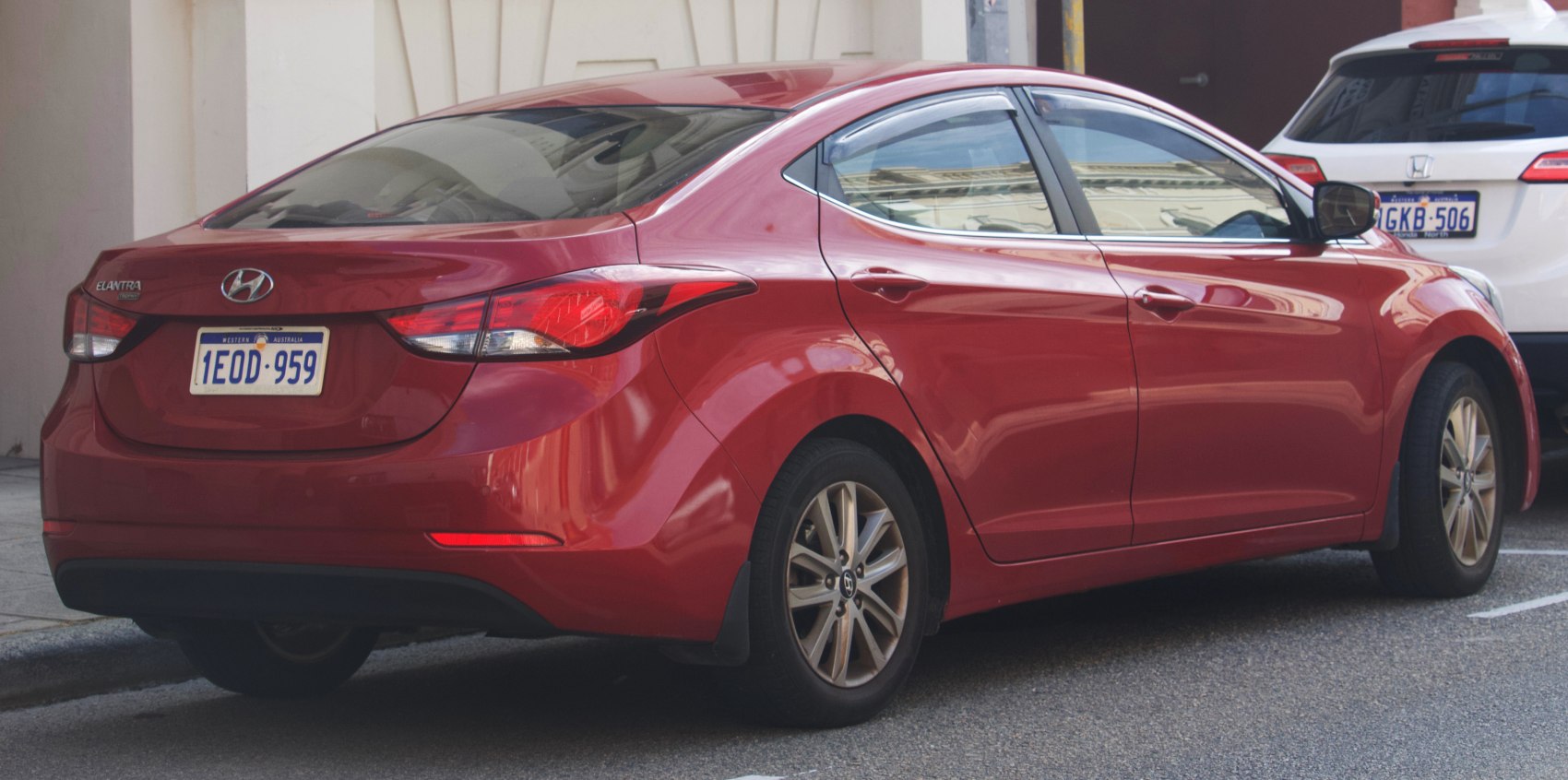 Rear side view with taillights and body contours of red sedan