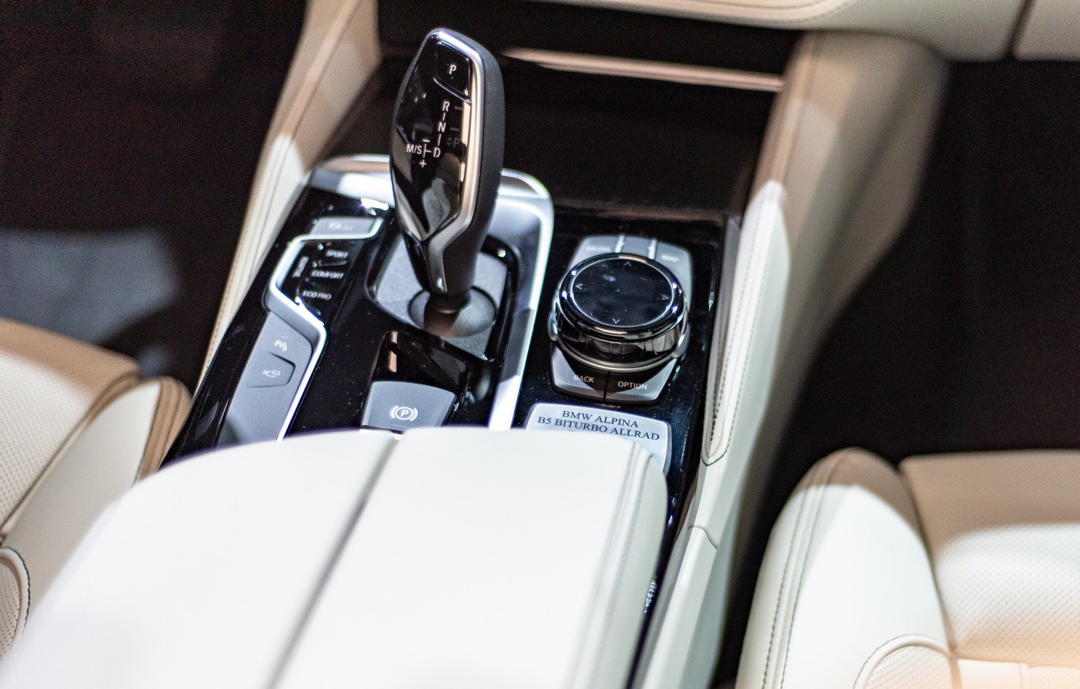 Automatic gear shifter and control knob on a beige leather center console