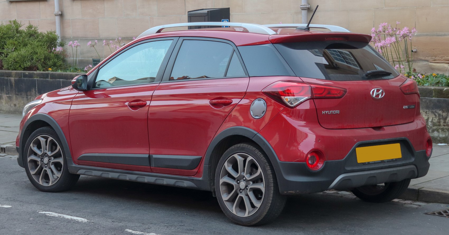 Red compact crossover SUV with roof rails and alloy wheels
