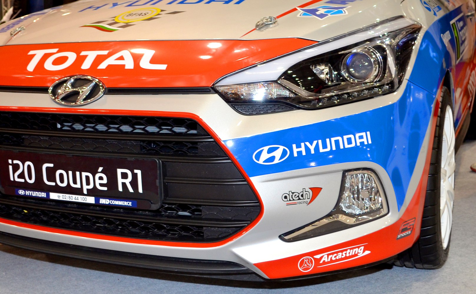 Close-up of rally car front grille, headlight, and sponsor decals