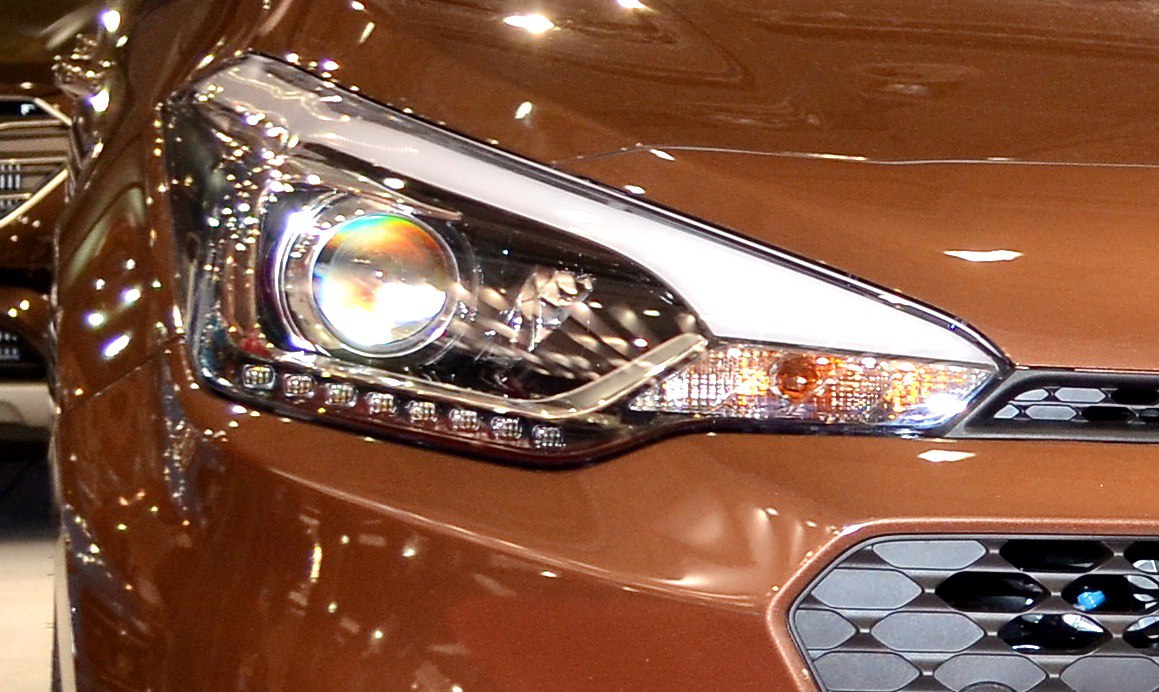 Close-up of a car front headlight with LED strip and honeycomb grille