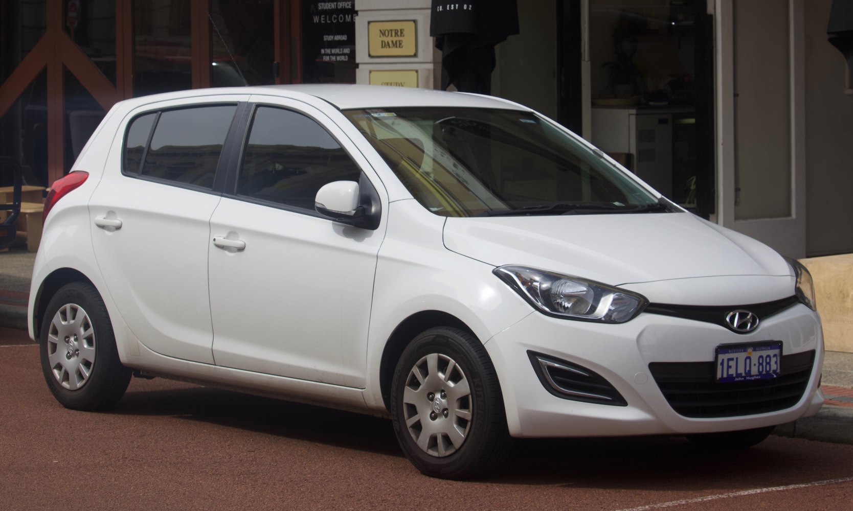 White compact hatchback with prominent headlights and grille.