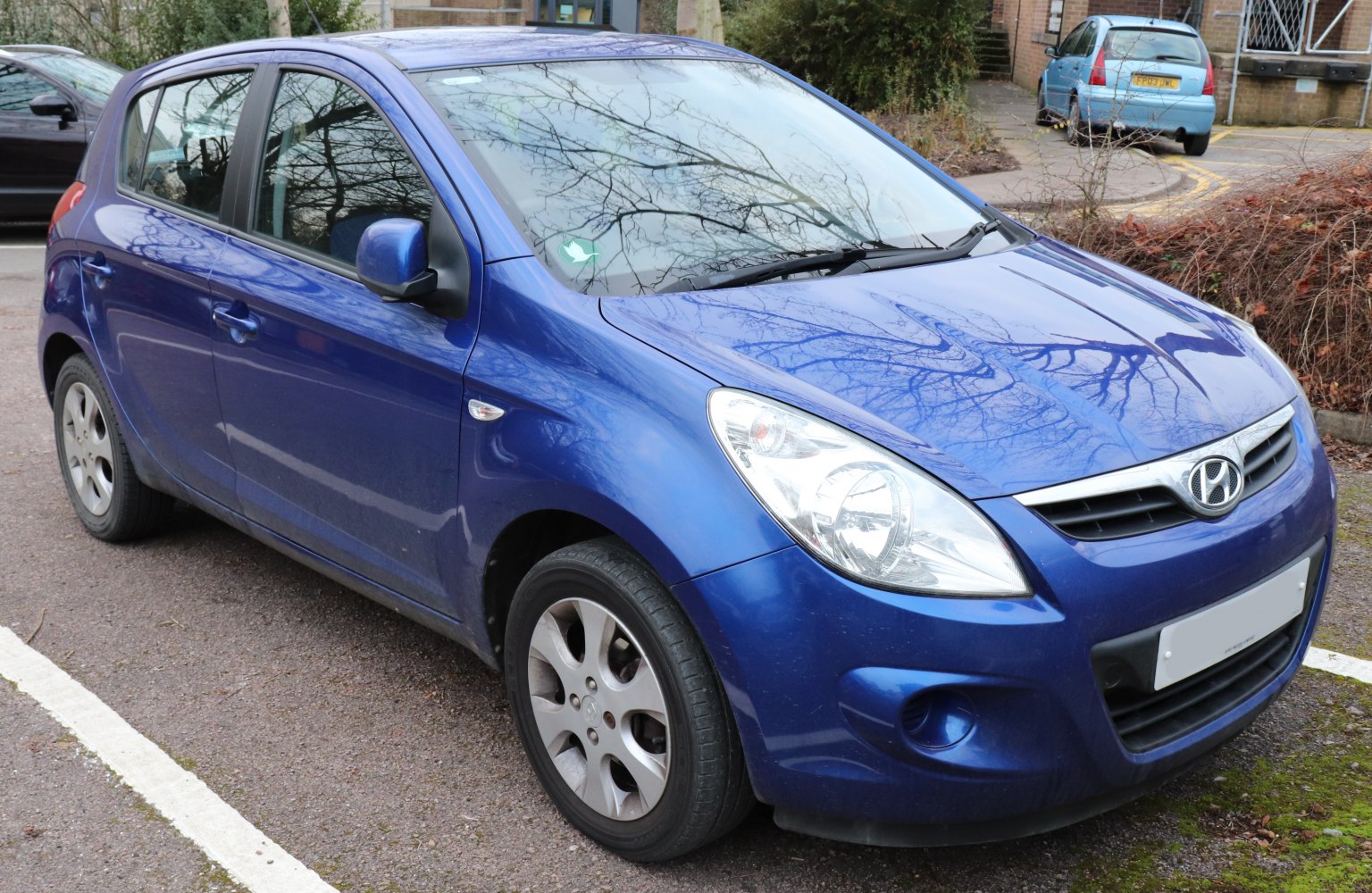 Blue compact hatchback front-side view with distinct headlights and grille