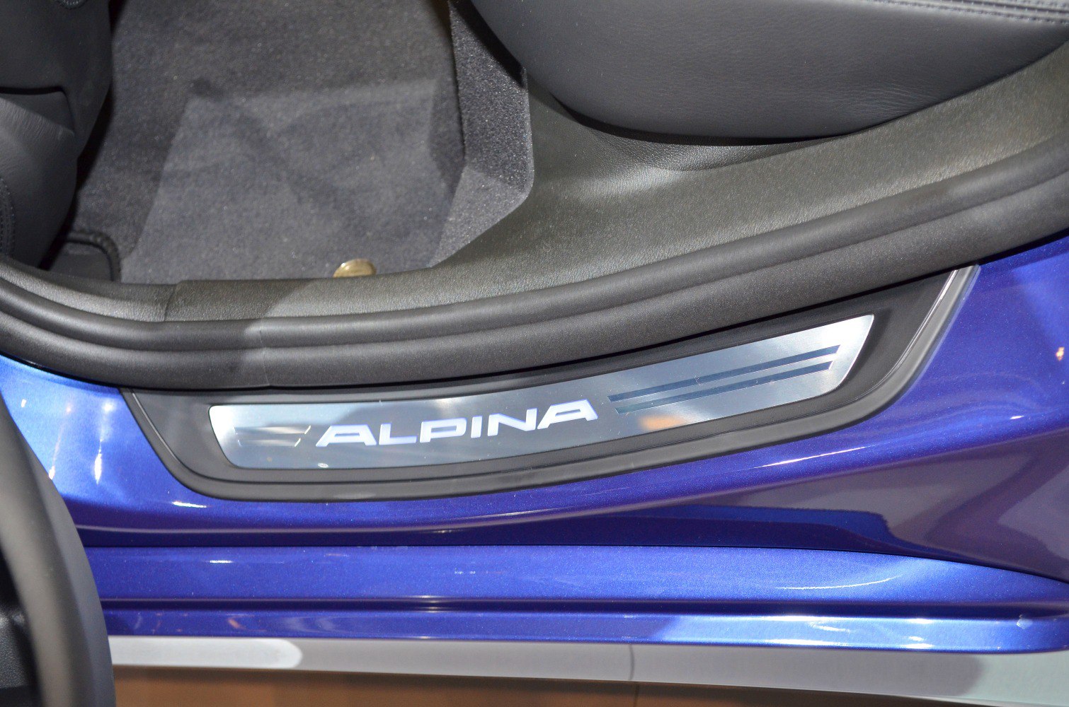 Illuminated Alpina door sill plate on blue car interior