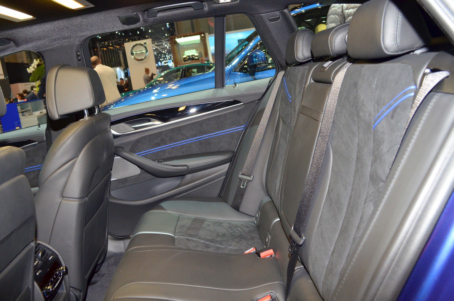 Rear passenger seats with black leather and Alcantara upholstery, accented with blue stitching.