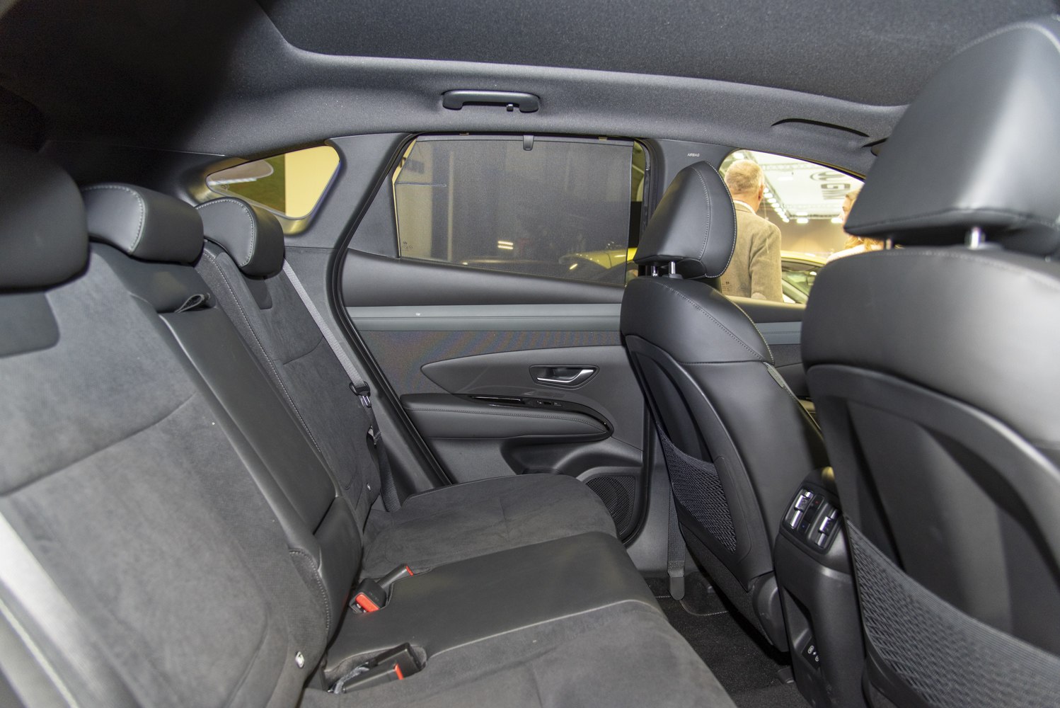 Rear passenger seating area with modern black upholstery and window shade