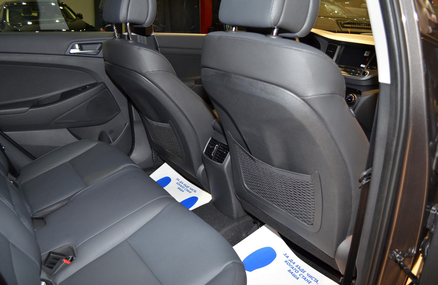 Rear black leather seats with mesh backrest pockets and central air vents.