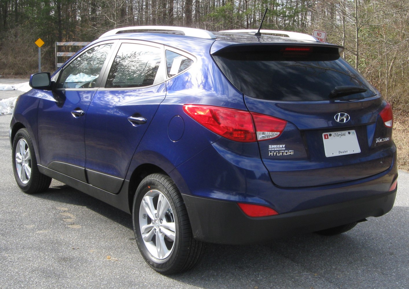Rear side profile of blue SUV with taillights and alloy wheels