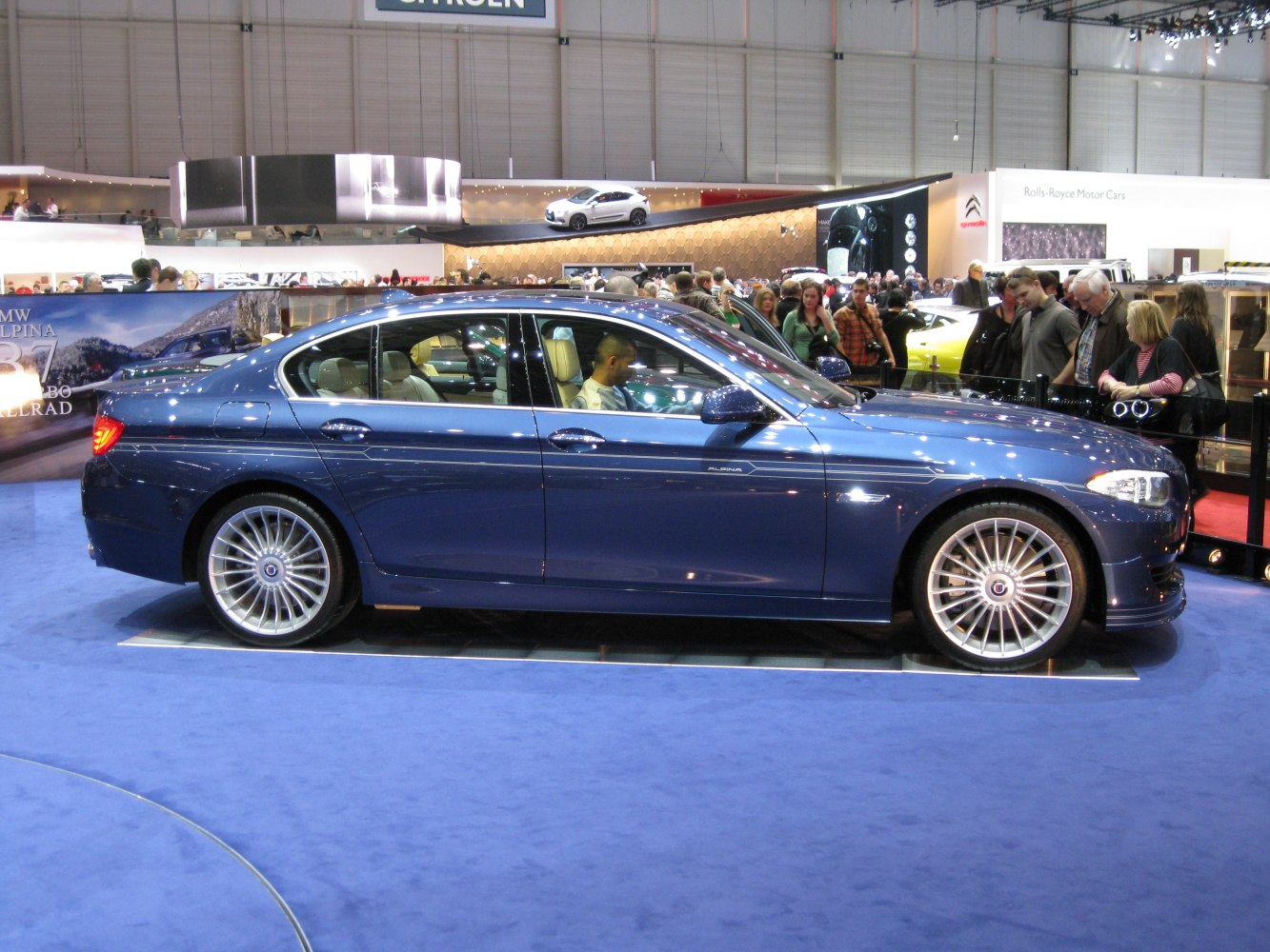 Side view of a luxury sedan with distinctive multi-spoke wheels
