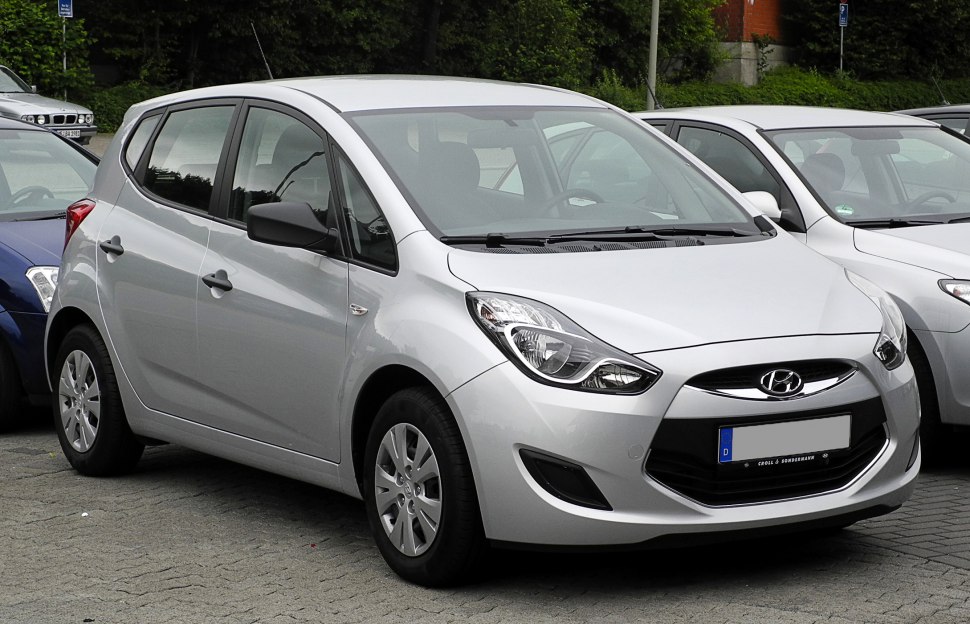 Front side view of compact hatchback with distinctive headlights and bold grille