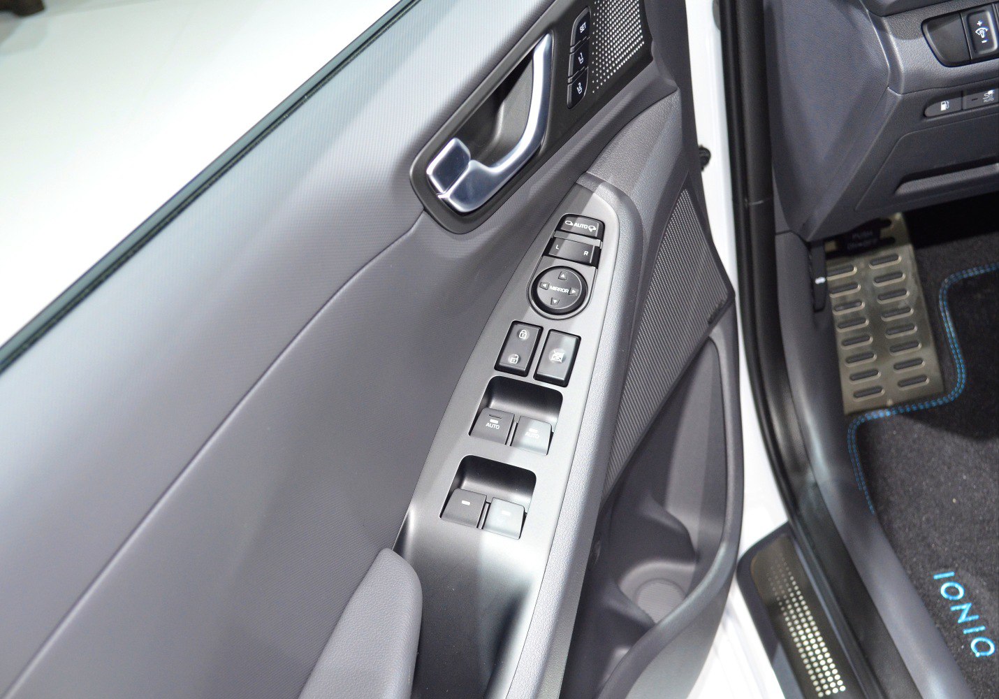Power window and mirror controls on door panel with metal pedals