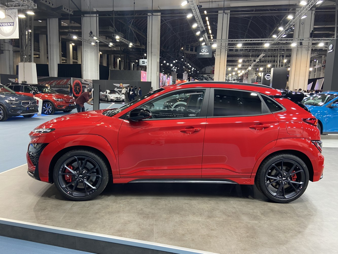 Side profile of a red compact SUV with black alloy wheels and sporty design.