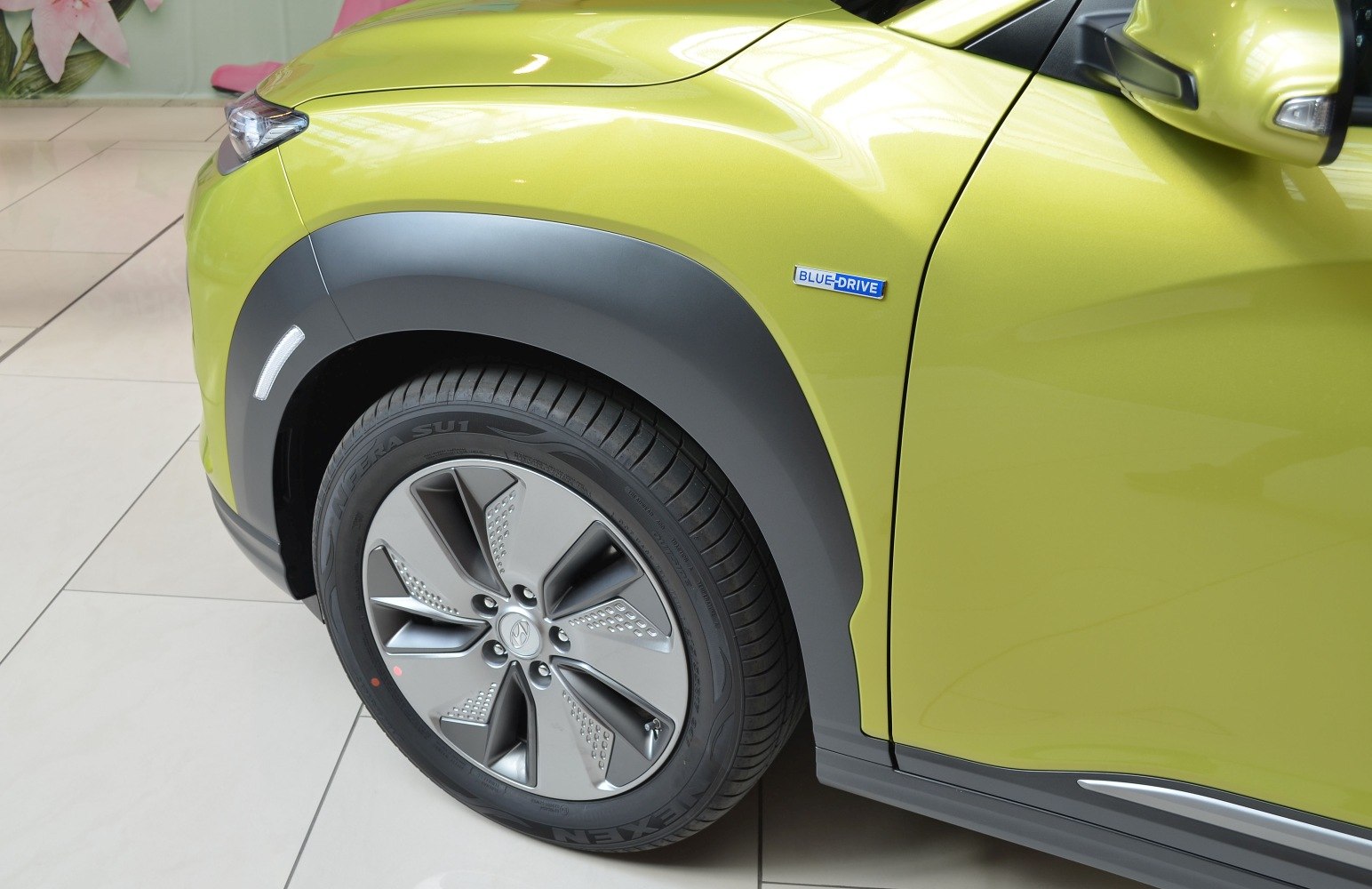 Front wheel and Blue Drive badge on green vehicle