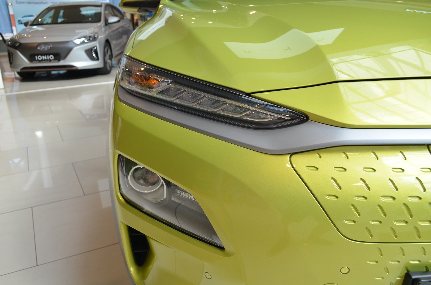 Close-up of front headlight and distinctive grille pattern.
