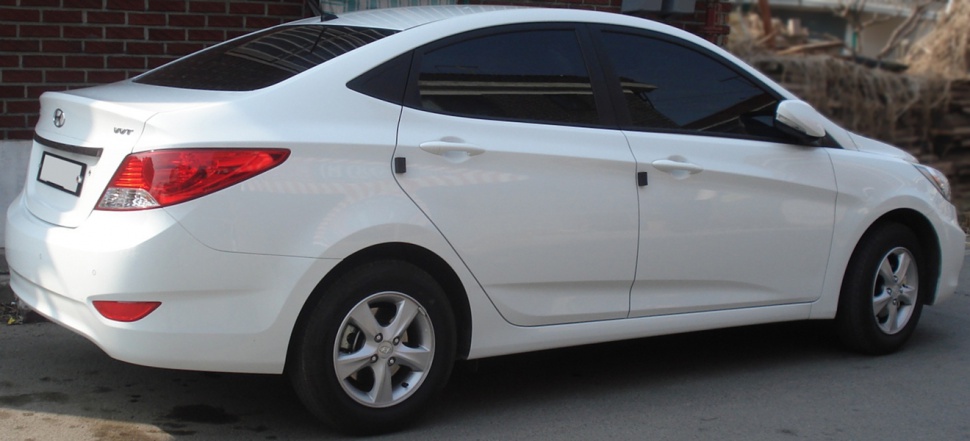 White sedan rear side view with tinted windows and alloy wheels