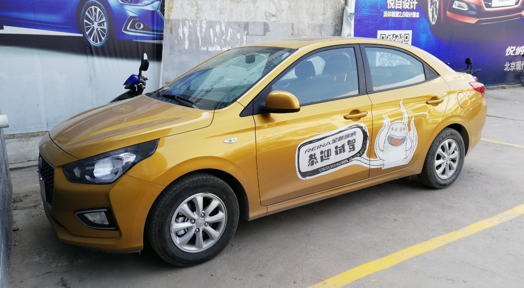 Gold sedan with alloy wheels and promotional cartoon decal