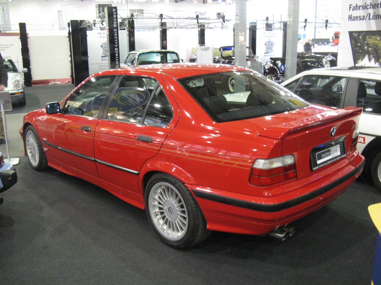 Red sedan with rear spoiler and multi-spoke alloy wheels