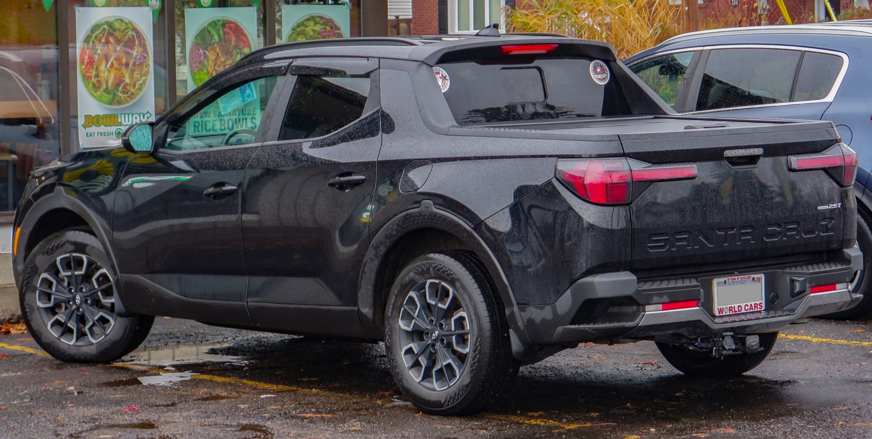 Black pickup truck with alloy wheels and covered bed rear view