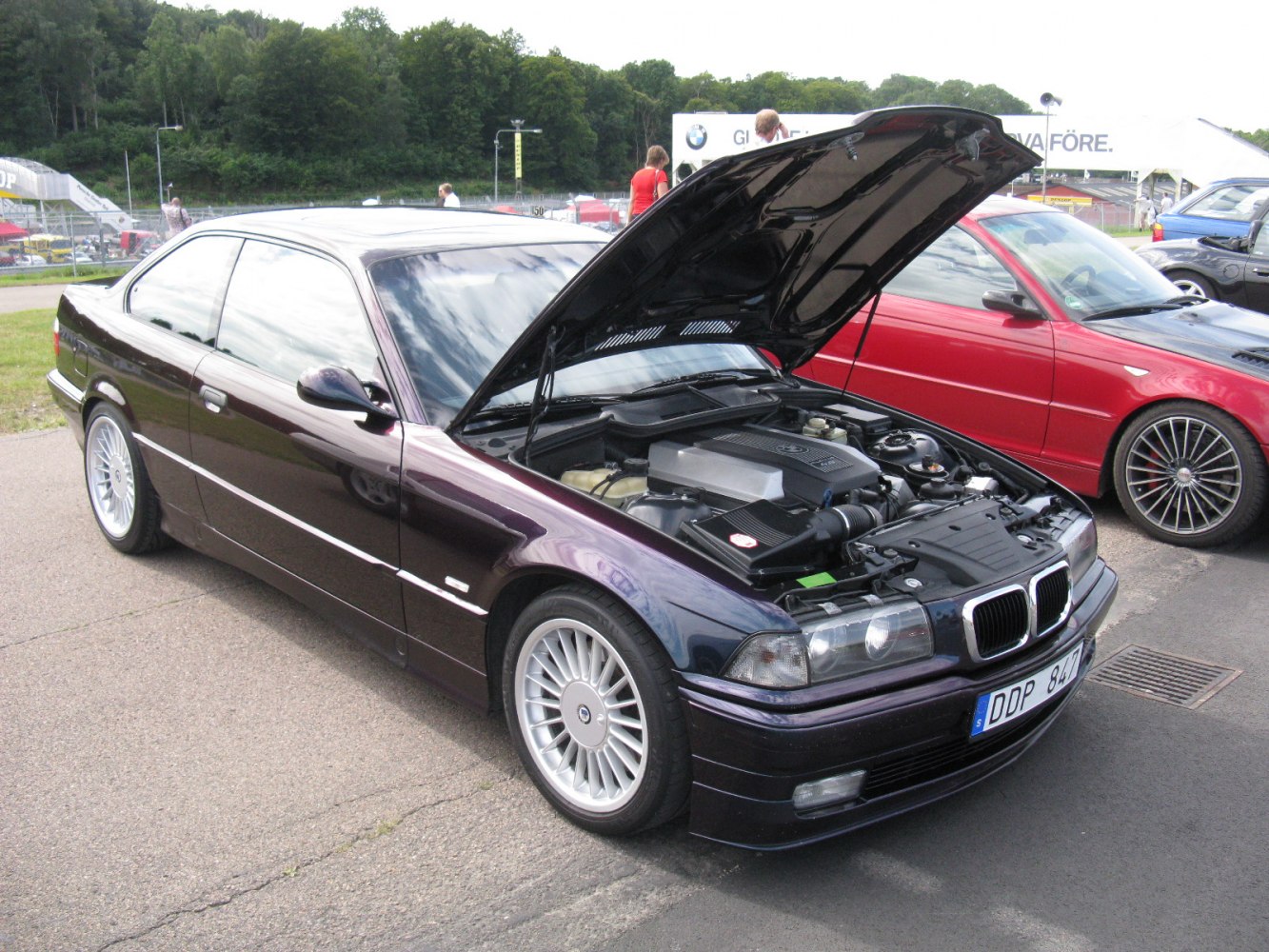 Classic coupe with open hood showing detailed engine and distinctive wheels
