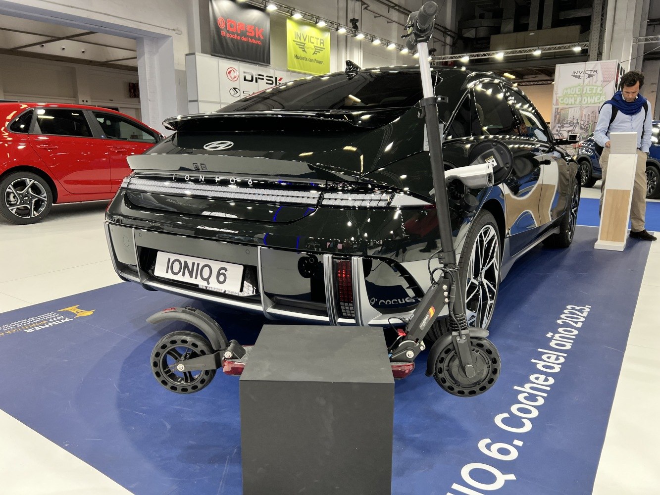 Rear view of electric sedan and electric scooter on display