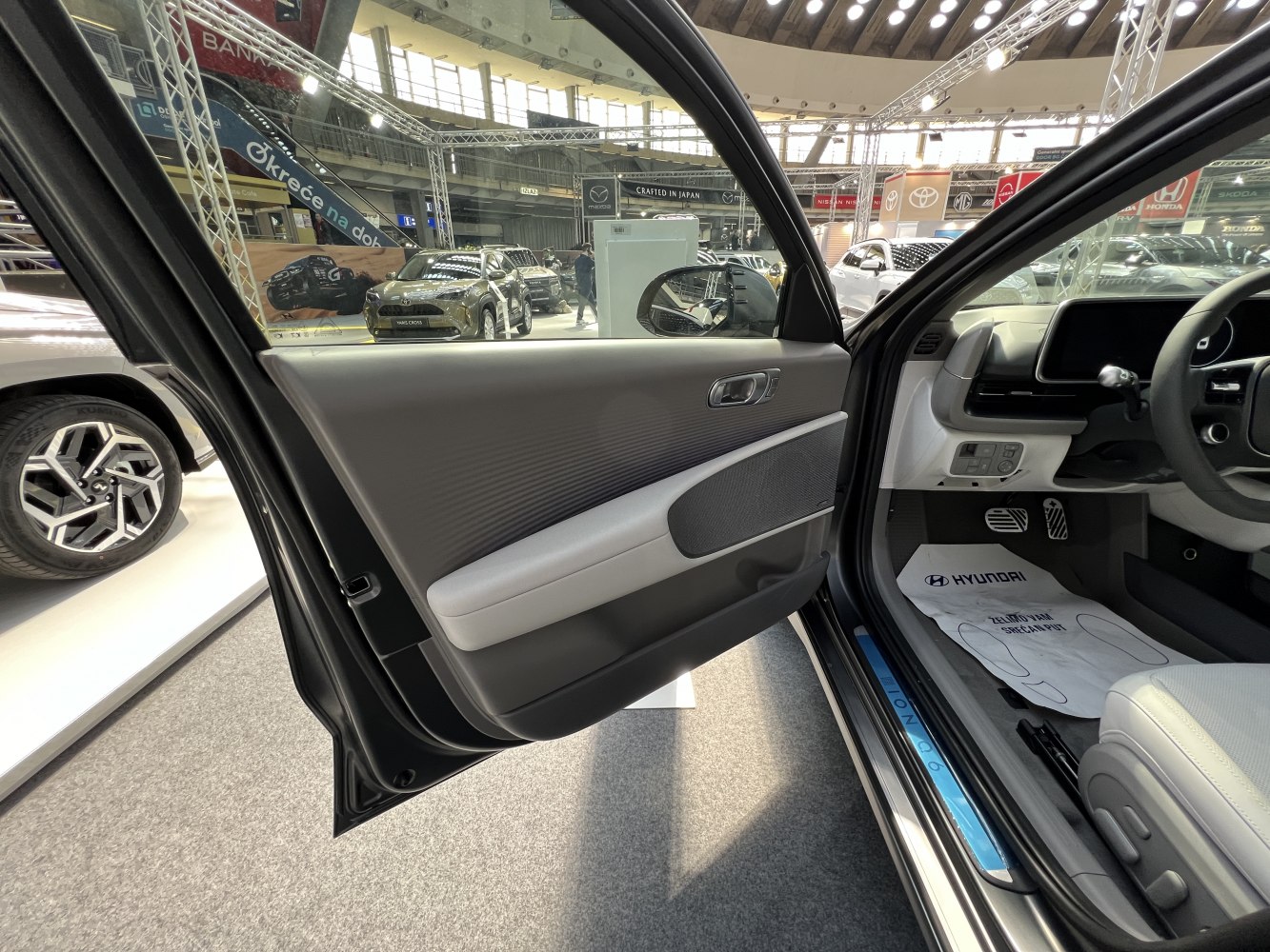 Driver door panel and footwell with pedals and floor mat in car interior