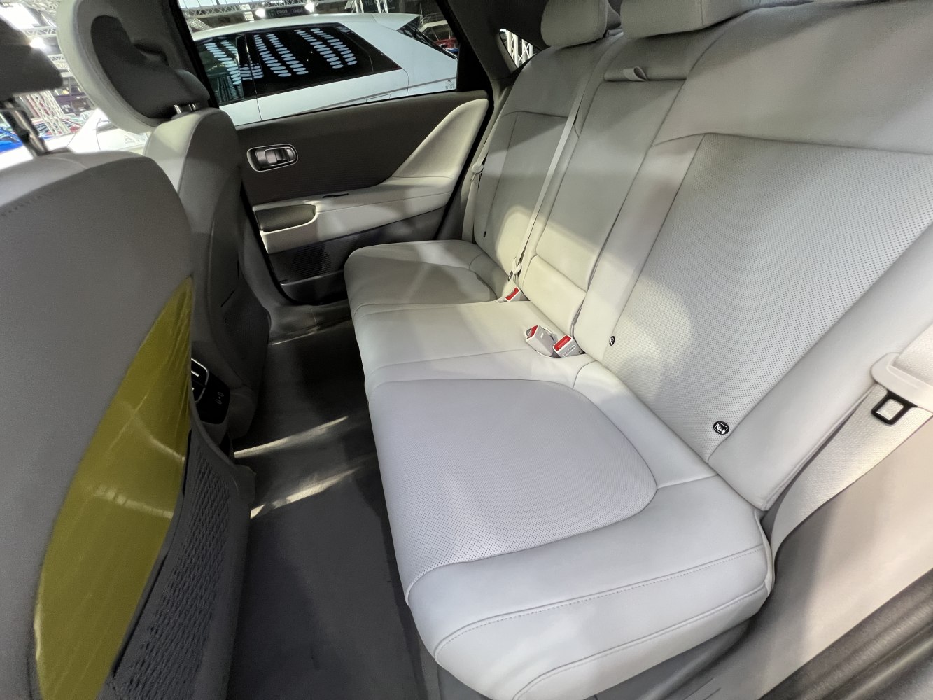 Modern rear seat interior with light upholstery and seatbelt buckles