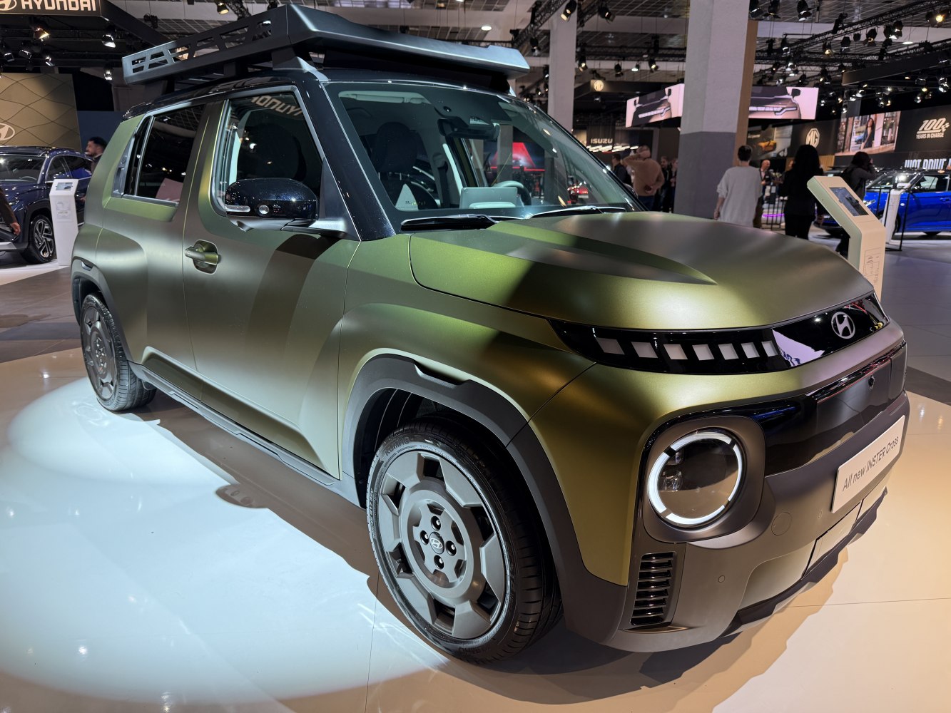 Matte green SUV with roof rack and rectangular LED headlights