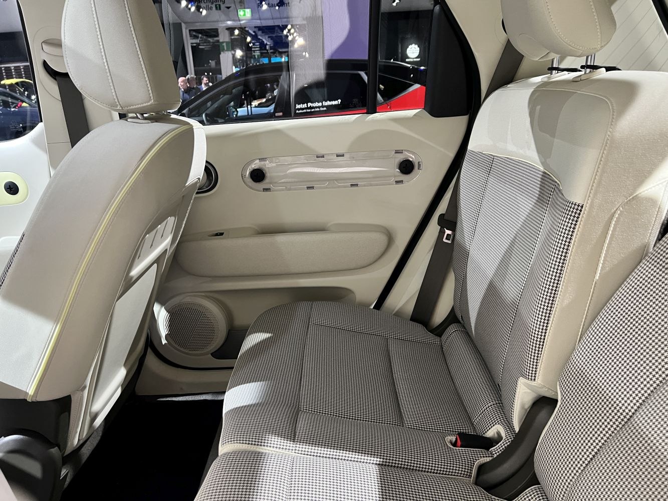 Rear seat and door panel interior with houndstooth upholstery and integrated speaker.