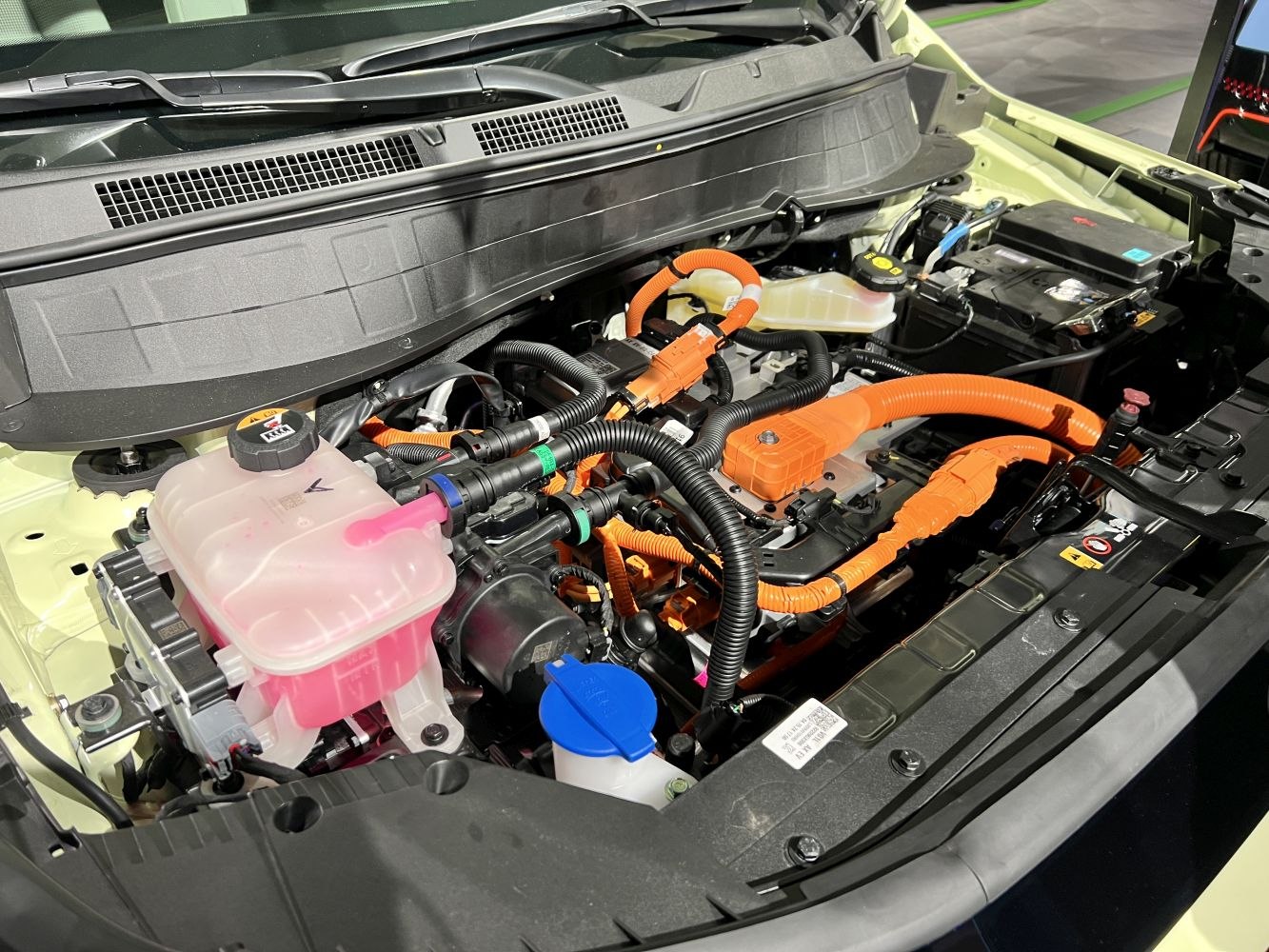 Electric engine bay with orange high-voltage cables and fluid reservoirs