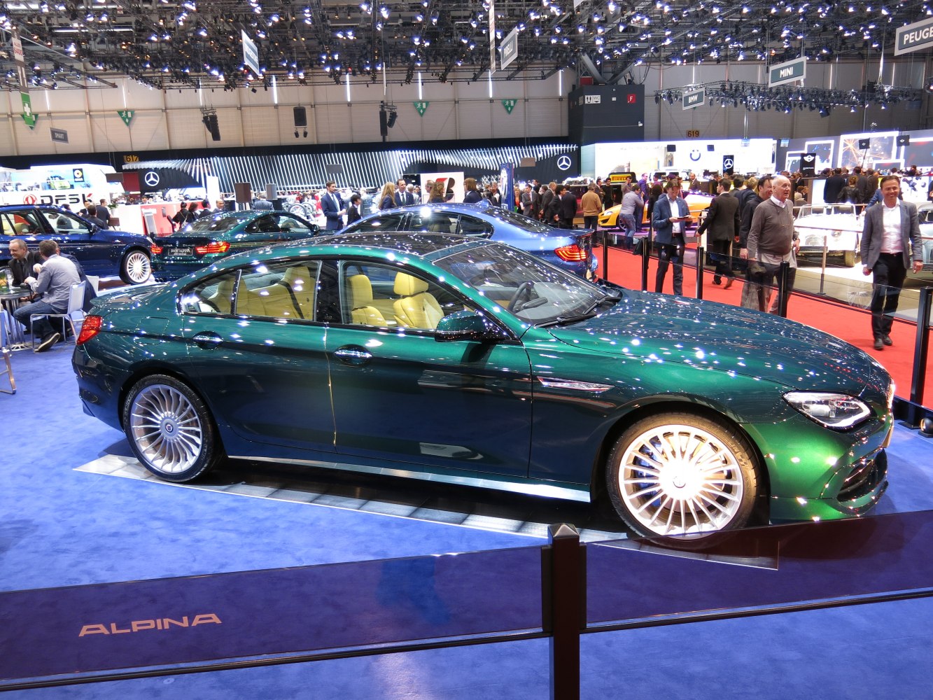 Sleek green four-door coupe with large multi-spoke wheels and beige leather seats