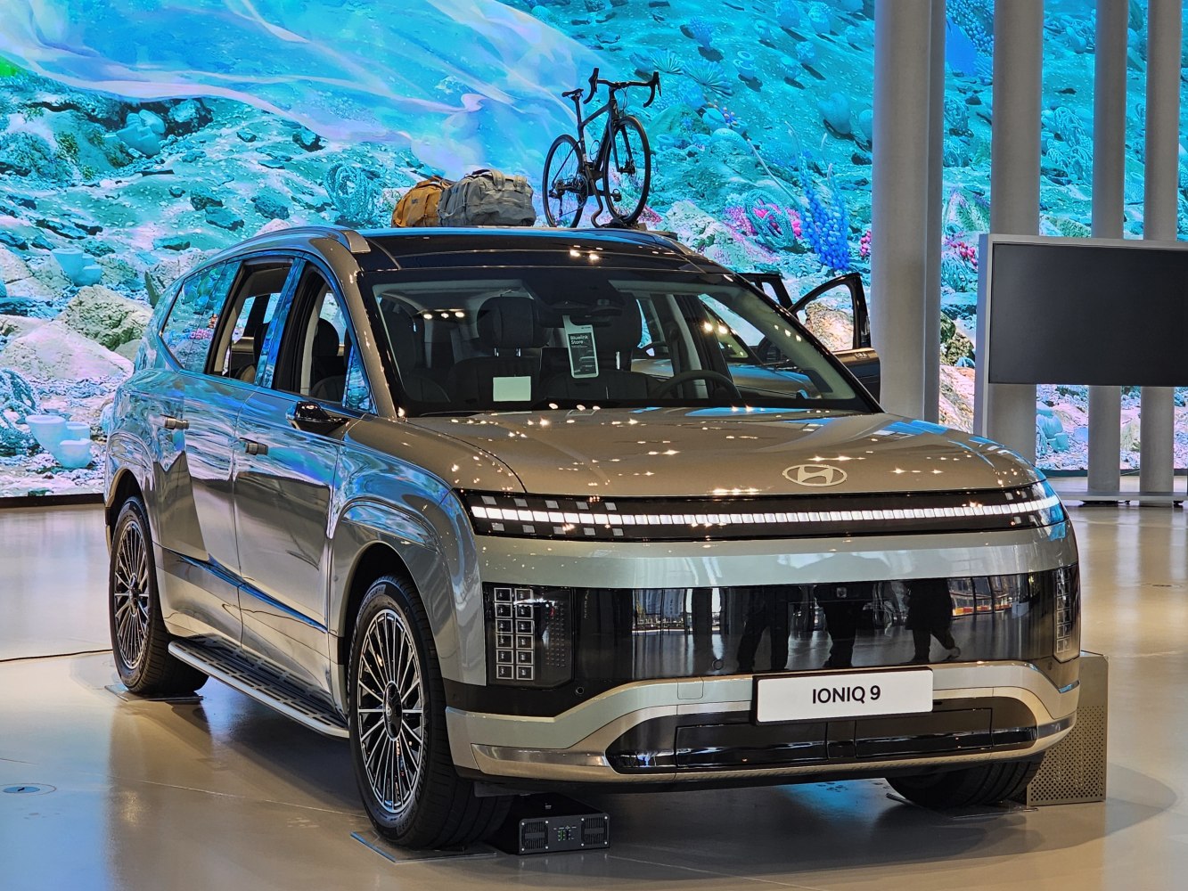 Electric SUV with roof bike and luggage rack, sleek LED lighting