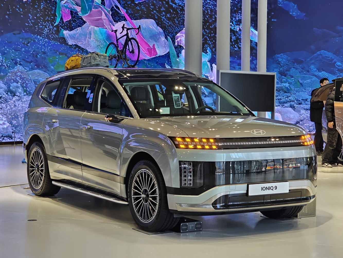Electric SUV with LED lights, roof bicycle, and luggage.