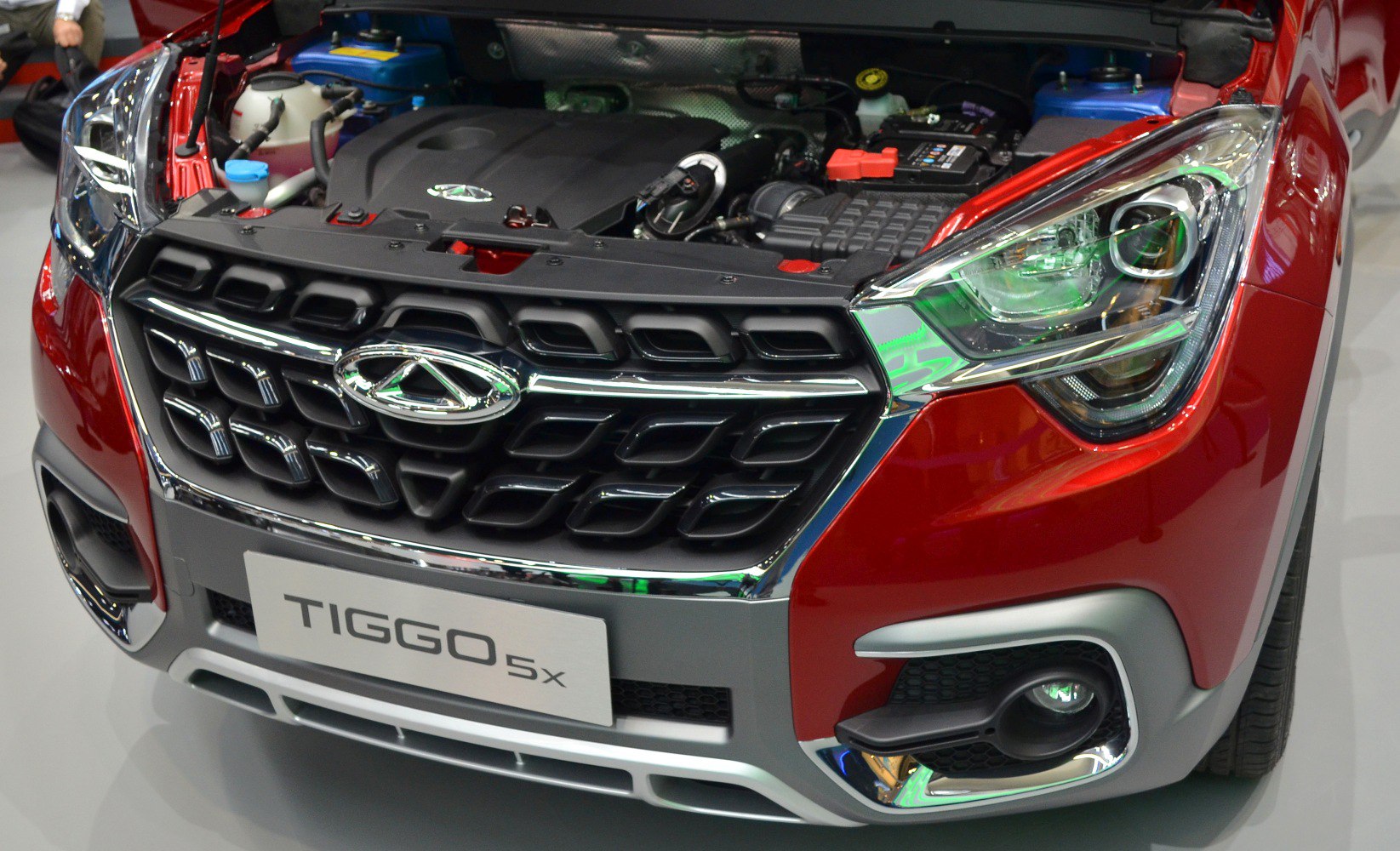 Front grille and headlight close-up with open hood showing engine bay