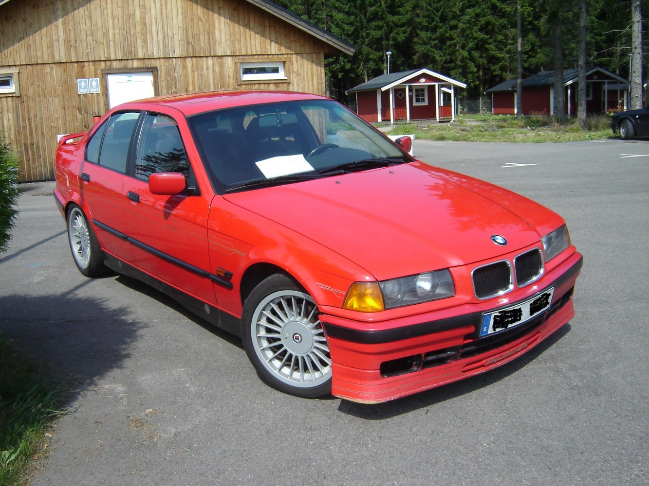 Red sedan with alloy wheels, rear spoiler, dual round headlights