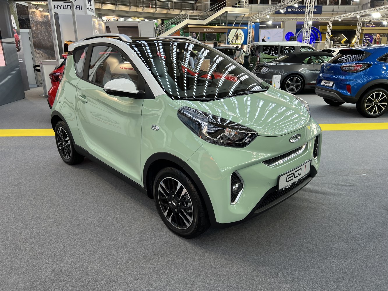 Compact electric vehicle front with modern headlights and sporty wheels