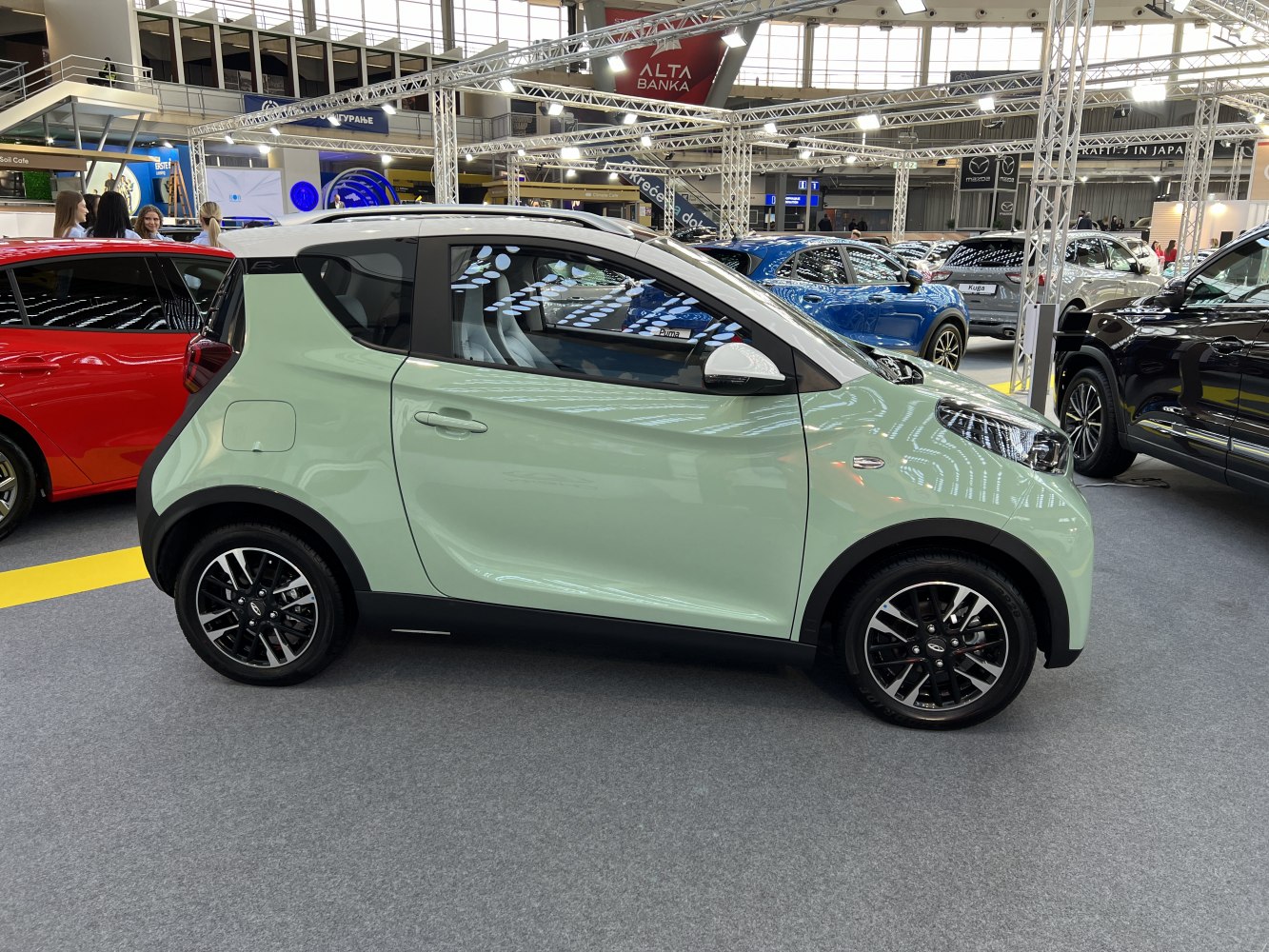 Compact electric microcar with two-tone green and white paint, viewed from the side.