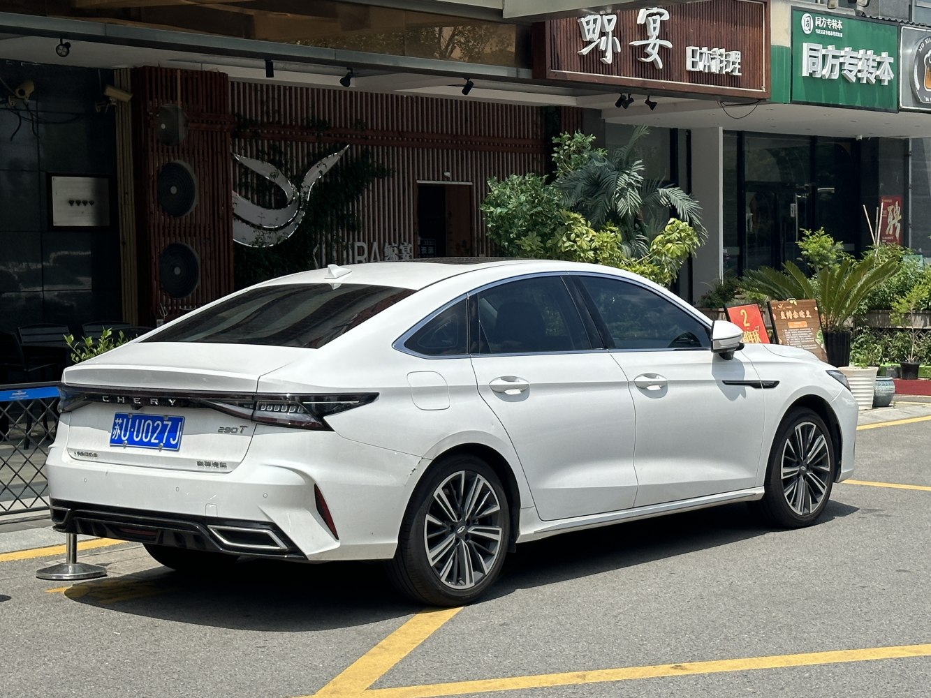 Rear view of a modern sedan with sleek tail lights and sculpted rear design.