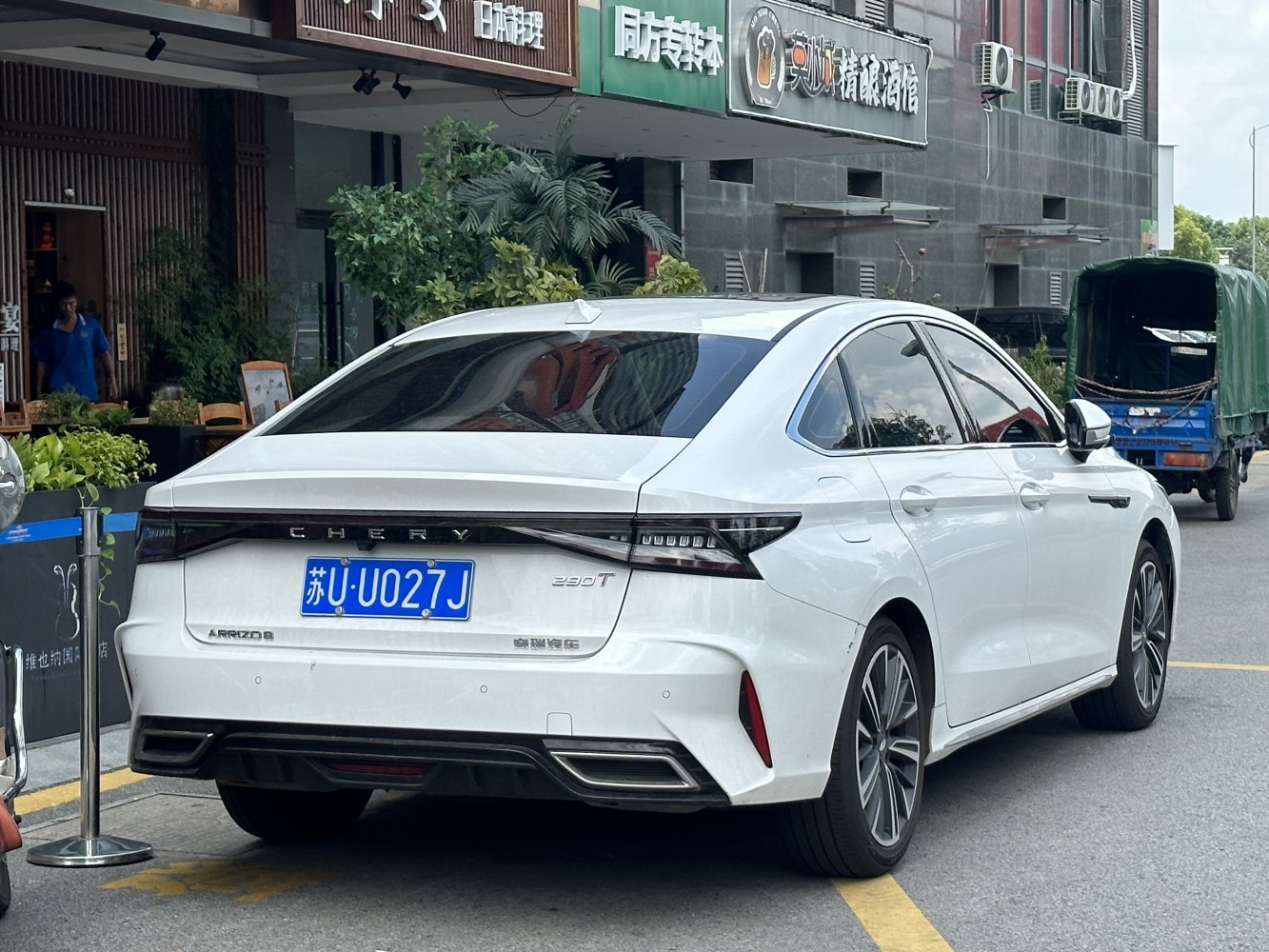 Rear view of sleek white modern sedan with integrated tail lights and dual exhaust design