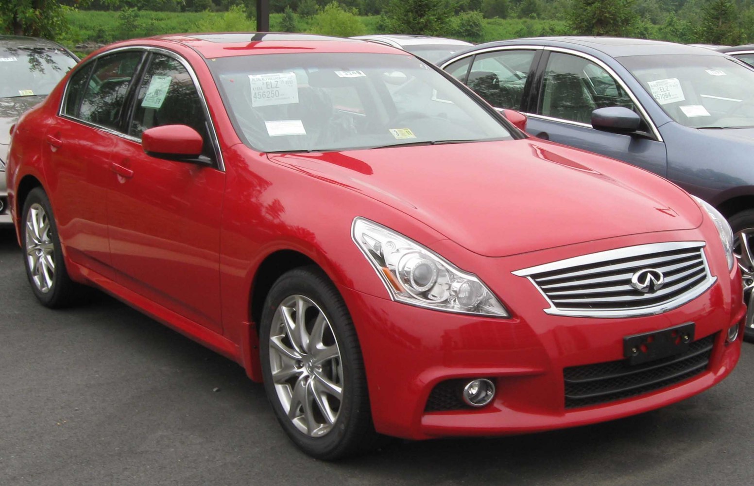 Red sedan showing front grille, projector LED headlights, alloy wheels, and fog lamps.