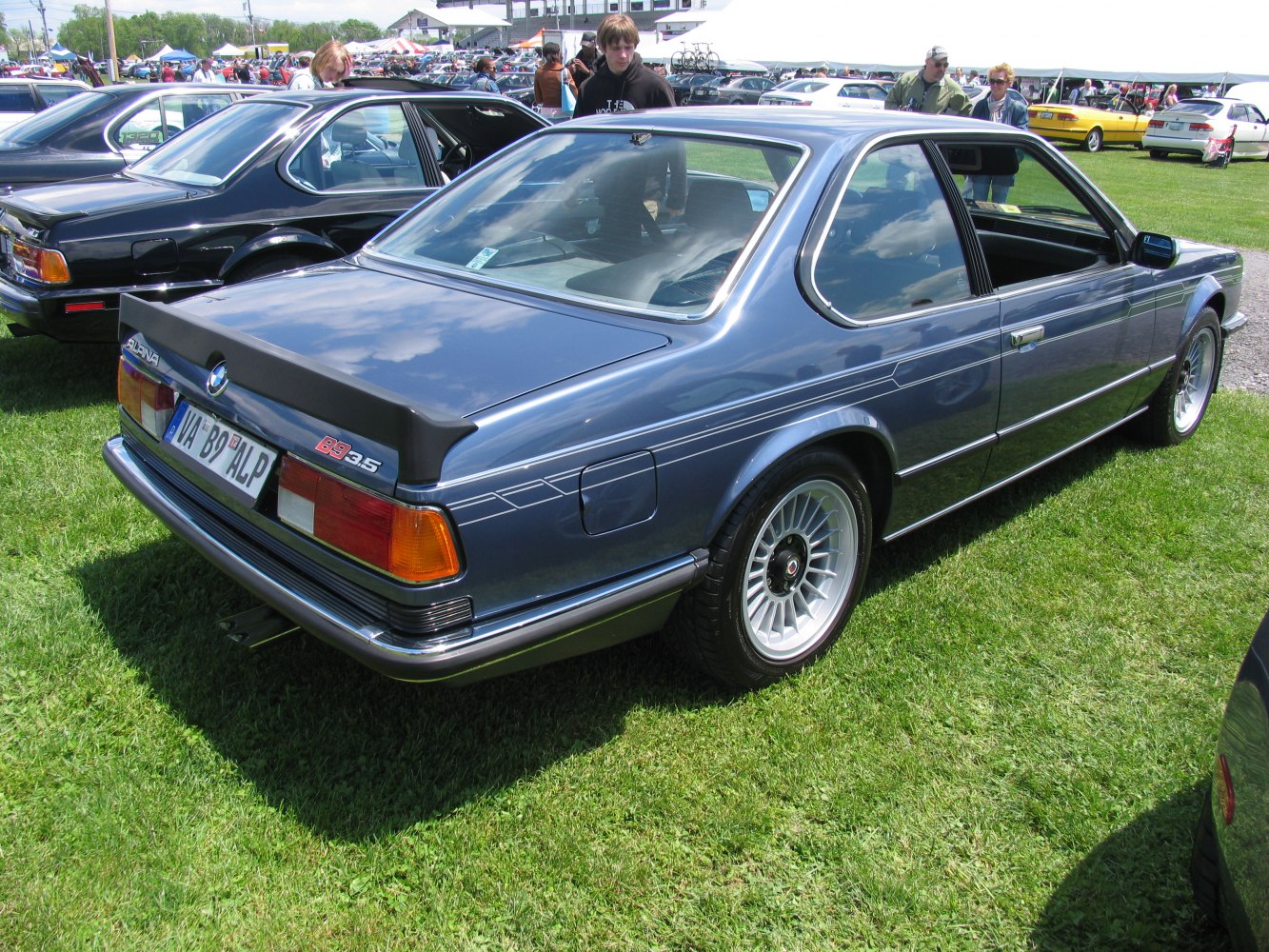 Rear and side view of classic coupe with rear spoiler and detailed alloy wheels.
