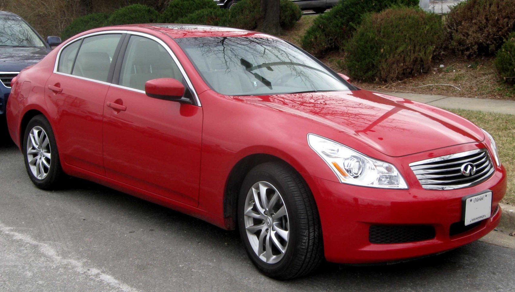 Front-side view of a red sedan with chrome grille and alloy wheels
