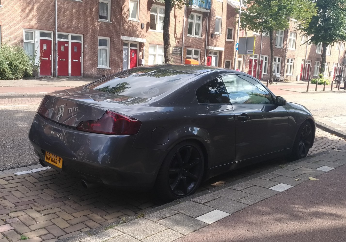 Rear side view of a sleek dark sports coupe with tinted windows and dark wheels