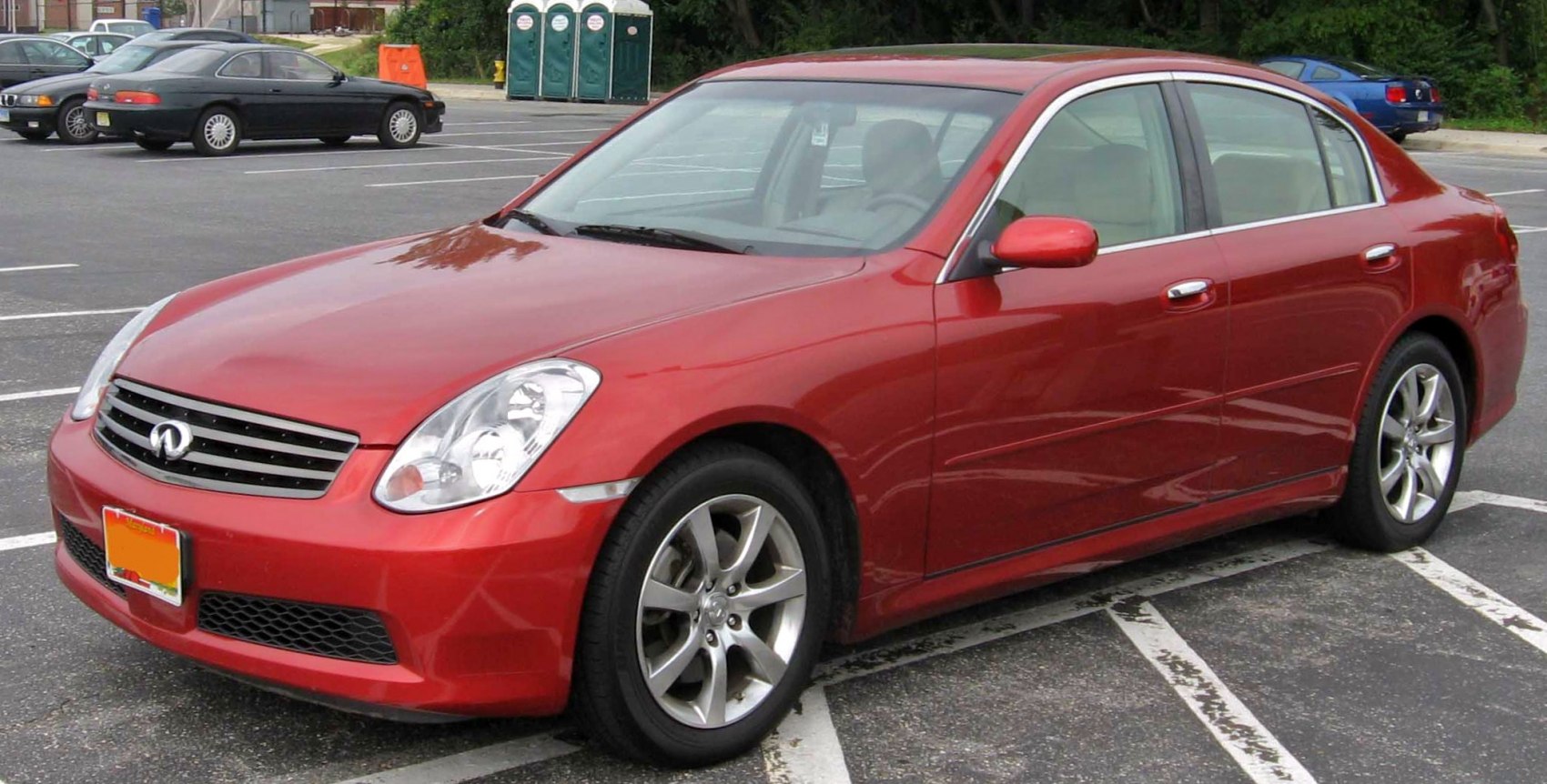 Red sedan with alloy wheels and distinctive headlights parked in a lot