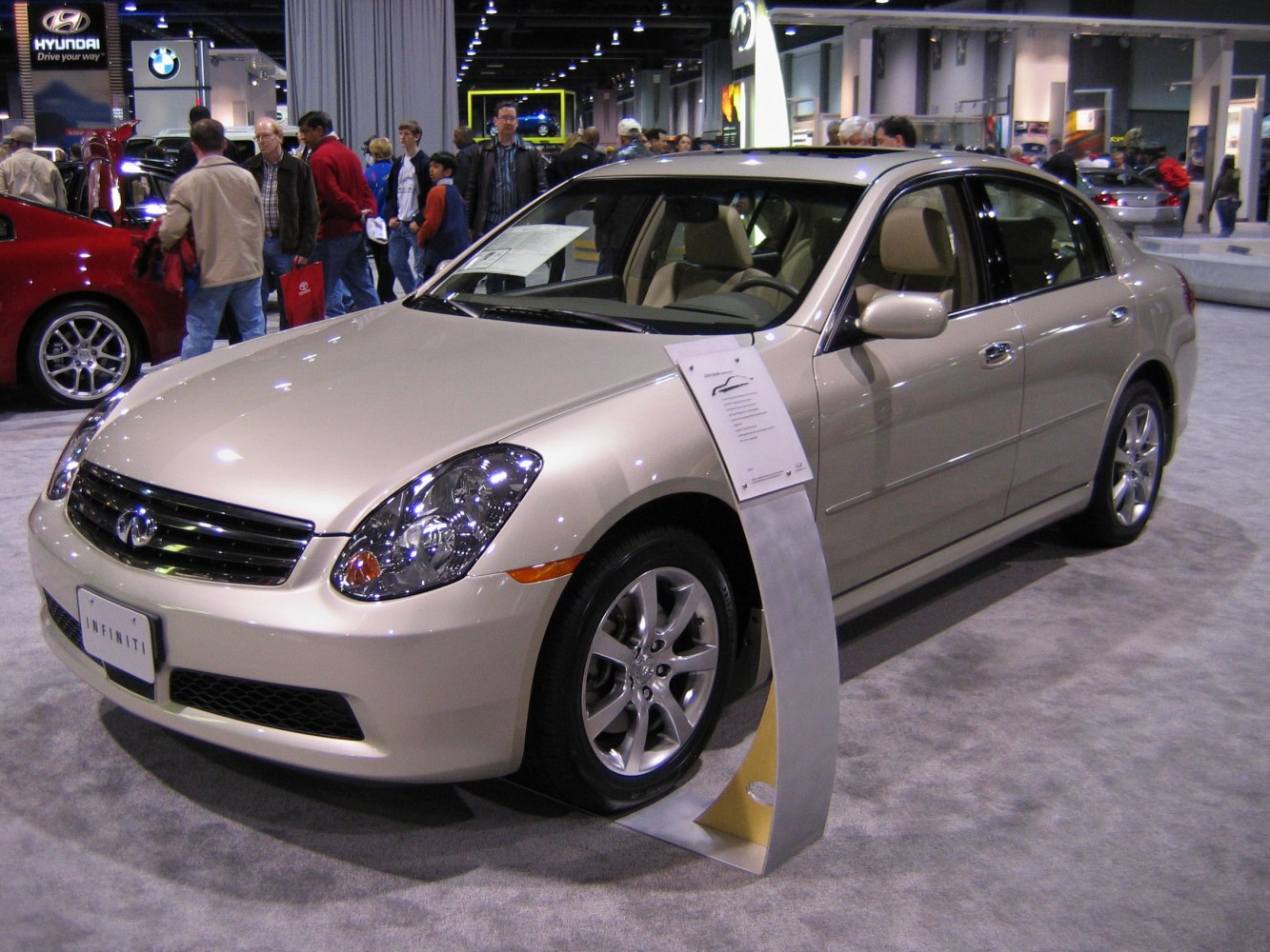 Front side view of beige sedan with alloy wheels at auto show