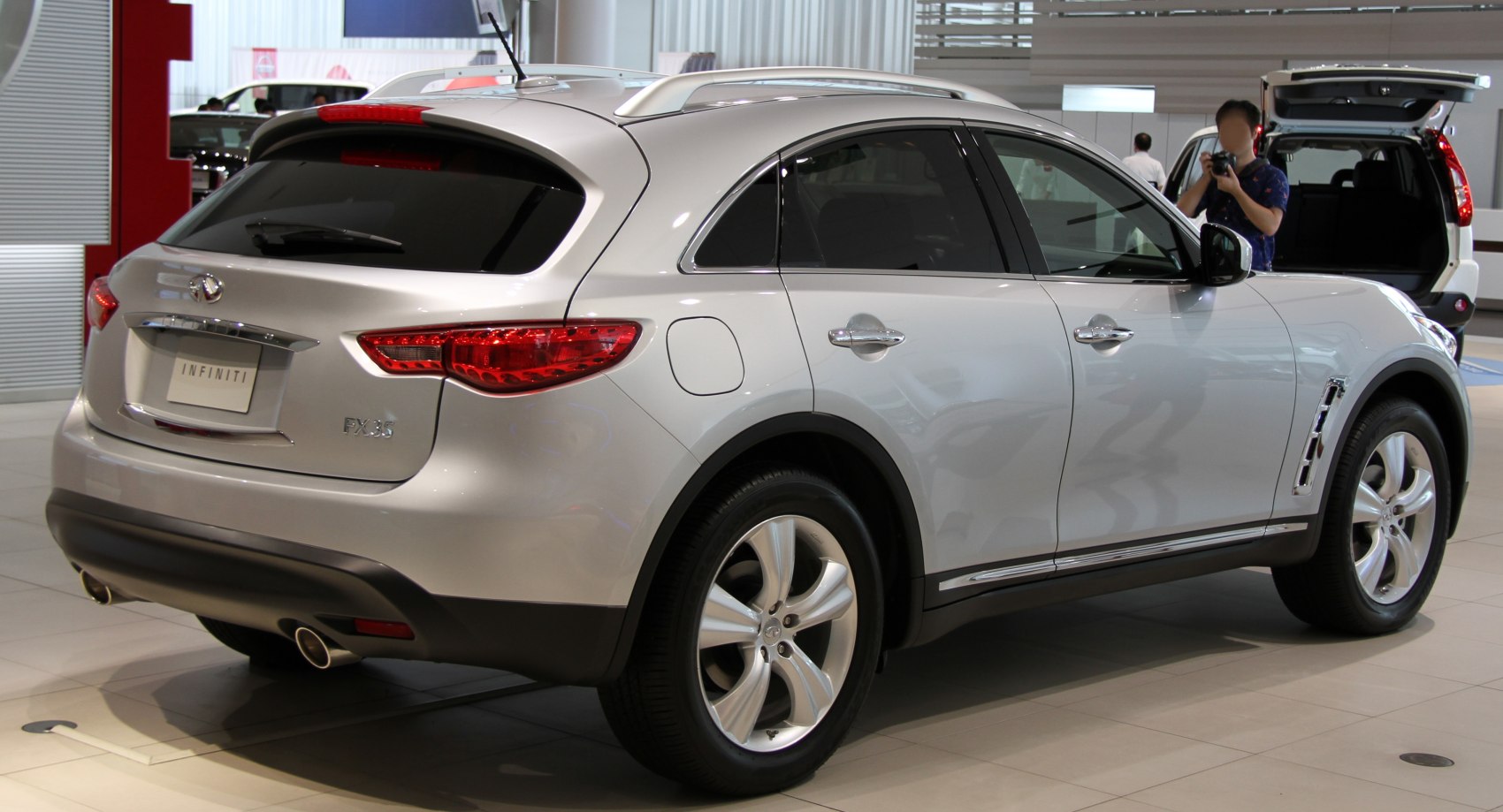 Rear quarter view with taillights, dual exhaust, alloy wheels, and roof rails.