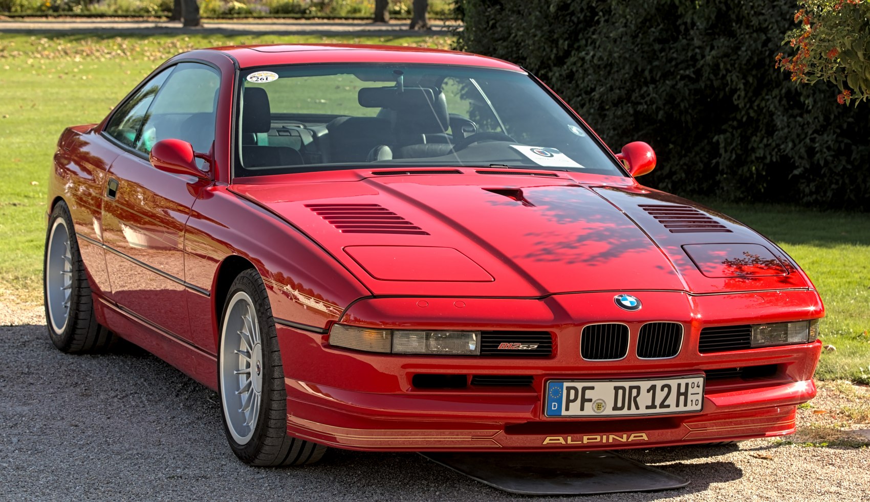Red coupe with vented hood and classic front design with distinctive lights.