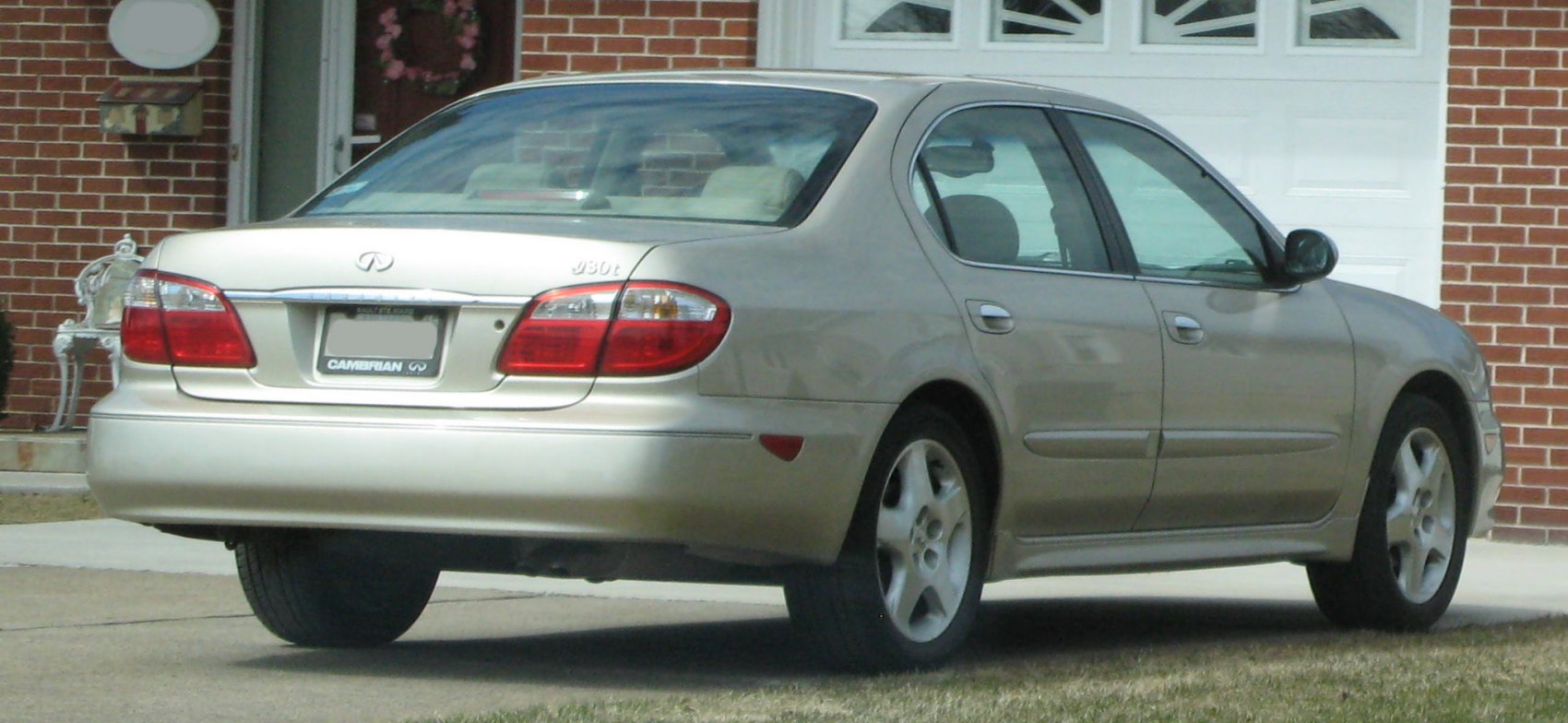 Rear and side view of a beige four-door sedan with alloy wheels and tail lights.