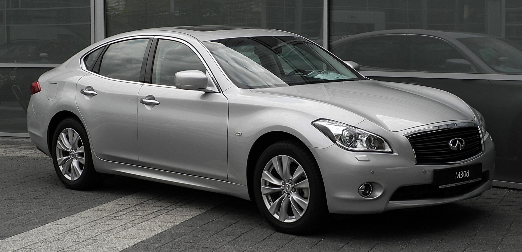 Front side view of silver sedan with alloy wheels and LED headlights